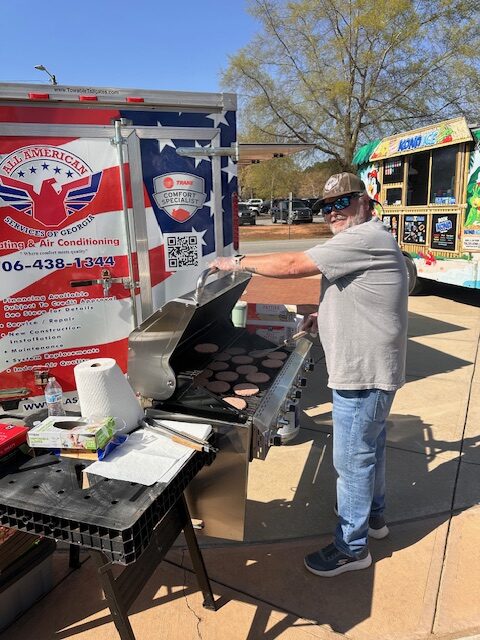 Man smiling and grilling at Community Event