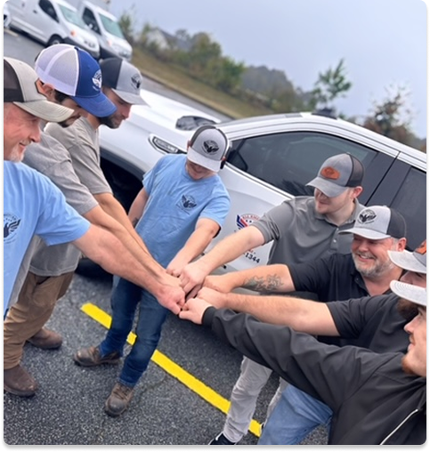 all american services of georgia employees stand in a circle with their hands in the center for a team meeting